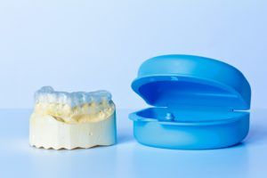 Dental mouth guard on a teeth model next to a plastic storage case